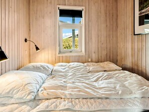 Et soveværelse med en seng, et vindue og en lampe monteret på væggen.