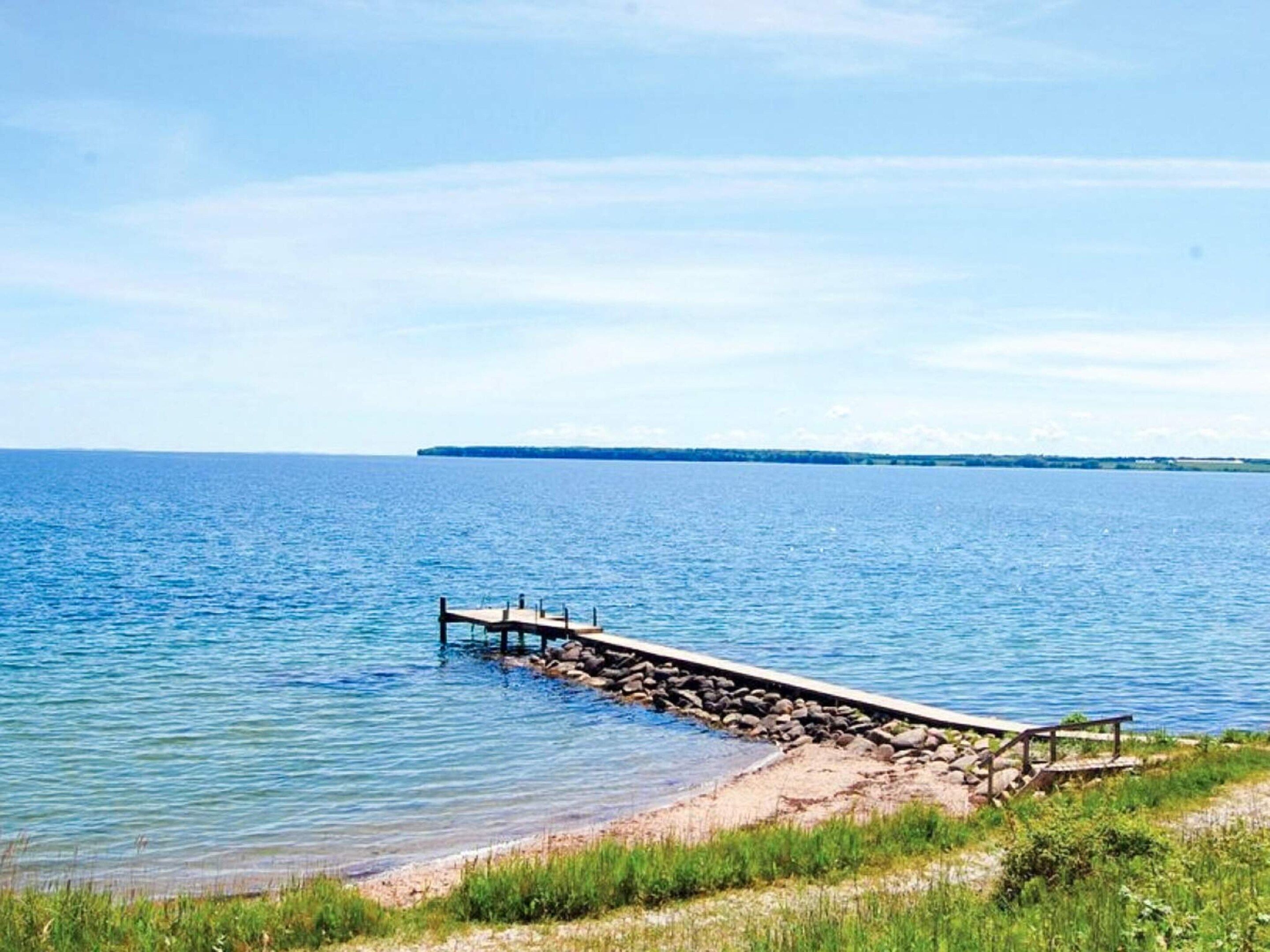 On peut clairement voir une étendue d’eau calme, avec une jetée en bois qui s’avance sur celle-ci.