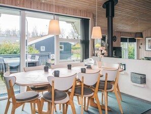 A modern kitchen with a large window, wooden ceiling, and a dining area with a table and chairs. - 5 Star Holiday Home in Juelsminde (Horsens)