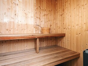 A wooden sauna with a bench and a bucket. - 5 Star Holiday Home in Juelsminde (Horsens)