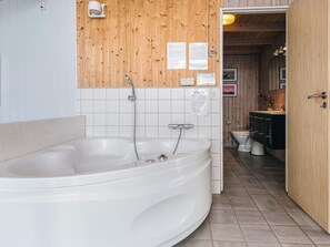 A modern bathroom with a large bathtub, wooden wall paneling, a toilet, and a sink. - 5 Star Holiday Home in Juelsminde (Horsens)