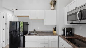 A modern kitchen with white cabinetry, a black refrigerator, a stainless steel sink, and a built-in microwave. - H Lakefront Property, Remodeled, Boat Slip, Patio Views, Pool, Ideal Location! (Osage Beach)