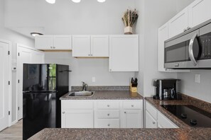 A modern kitchen with white cabinetry, a black refrigerator, a stainless steel sink, and a built-in microwave. - H Lakefront Property, Remodeled, Boat Slip, Patio Views, Pool, Ideal Location! (Osage Beach)