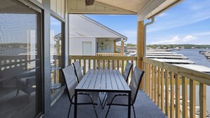 A covered outdoor area with a table and chairs, overlooking a marina with boats. - H Lakefront Property, Remodeled, Boat Slip, Patio Views, Pool, Ideal Location! (Osage Beach)