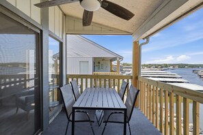 A covered outdoor area with a table and chairs, overlooking a marina with boats. - H Lakefront Property, Remodeled, Boat Slip, Patio Views, Pool, Ideal Location! (Osage Beach)