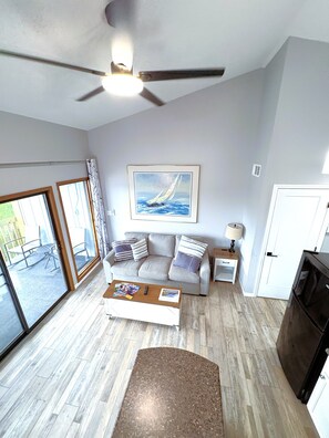 A living room with a ceiling fan, a sofa with cushions, a coffee table, and a painting on the wall. - H Lakefront Property, Remodeled, Boat Slip, Patio Views, Pool, Ideal Location! (Osage Beach)