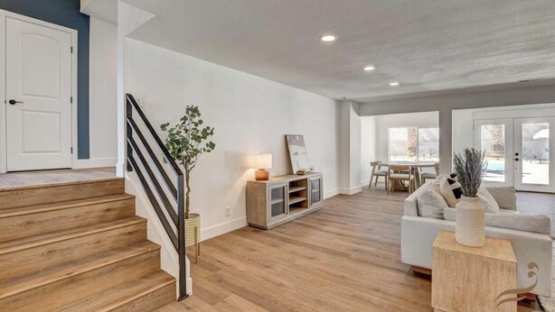 En rummelig opholdsstue med trappe, sofa, sofabord og spiseplads.