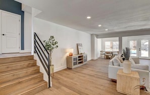 Ein geräumiger Wohnbereich mit Treppe, einer Couch, einem Couchtisch und einem Essbereich.