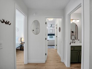 A hallway leading to a bedroom with a bed, a bathroom with a sink, and a mirror. - Cozy Mountain Condo @ Continental Golf Club (Flagstaff)