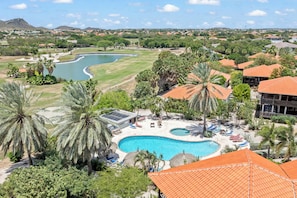 A resort with a swimming pool, palm trees, and a view of a river. - The Village 52 Blue Bay Golf and Beach Resort (Blue Bay)