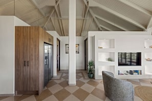 A spacious living area with a high ceiling, a wooden wardrobe, a grey sofa, and a television on a white wall. - The Village 52 Blue Bay Golf and Beach Resort (Blue Bay)