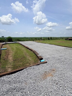 A gravel area with a grassy patch and a blue pipe.