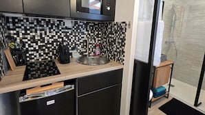 Una cucina compatta con forno a microonde, lavello e pensili neri.