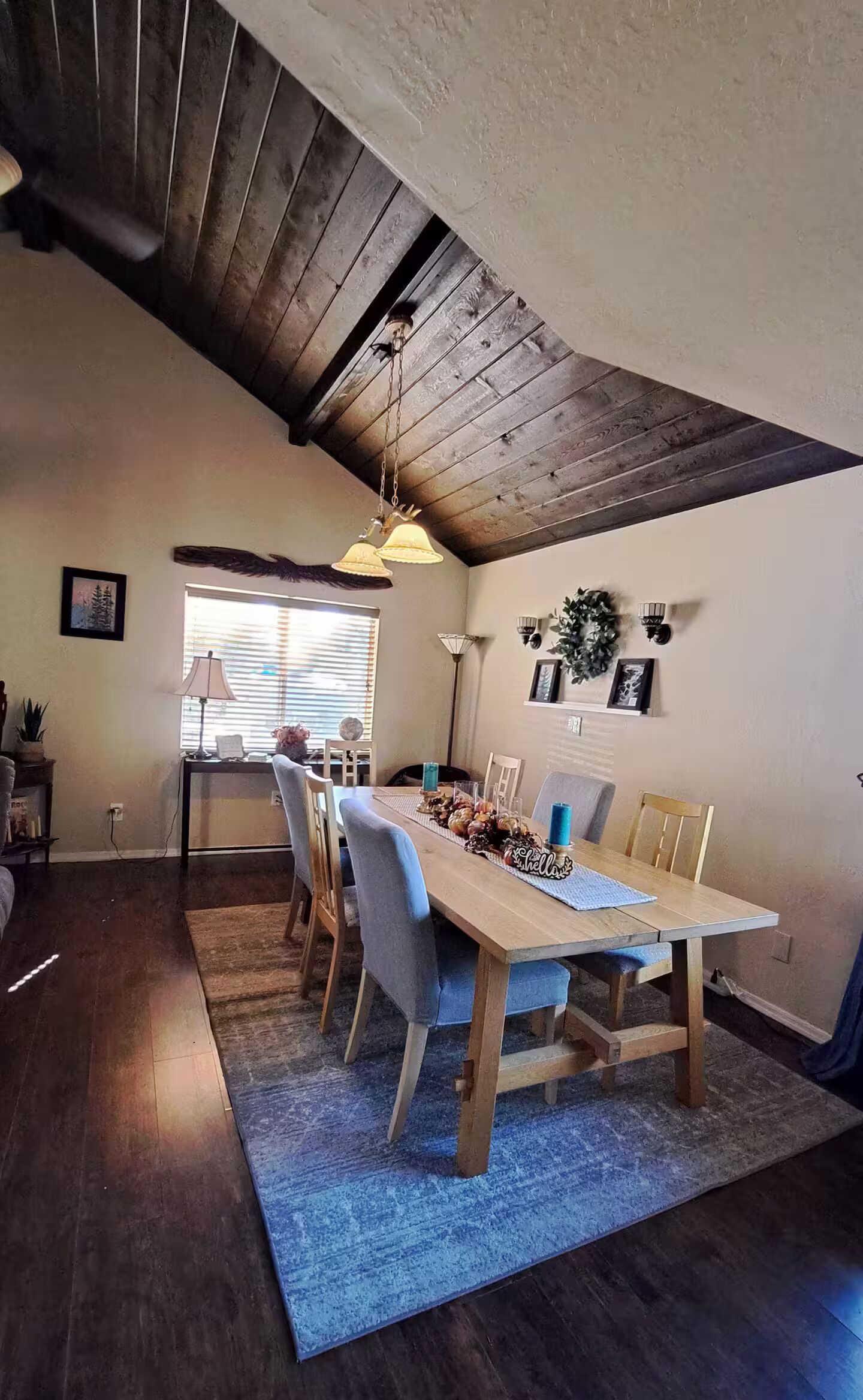 Ein Essbereich mit Holztisch, Stühlen und einer Decke mit sichtbaren Holzbalken.