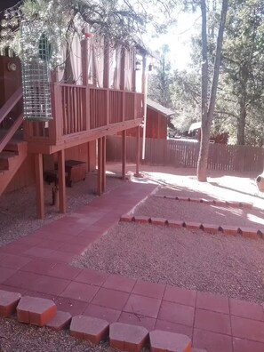Eine Holzterrasse mit Geländer, einem Vogelhaus und einem eingezäunten Bereich.