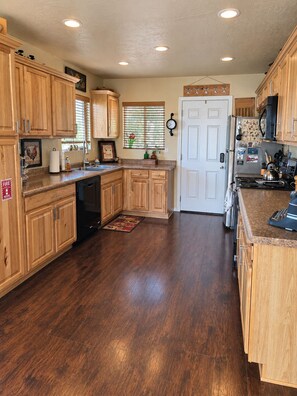 A kitchen with wooden cabinets, a refrigerator, a stove, and a dishwasher.