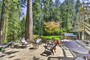 Een terras met buitenmeubilair, een barbecue en een grote boom.