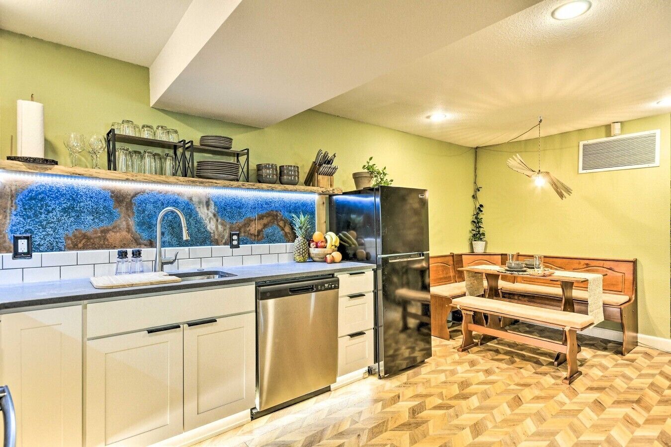 Une cuisine équipée d’un lave-vaisselle, d’un réfrigérateur et d’un coin repas avec une banquette.