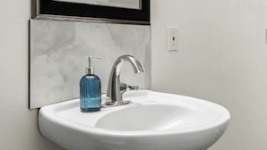 Een wit badkamermeubel met een moderne kraan en een blauwe zeepdispenser.