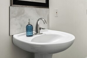 A white bathroom sink with a modern faucet and a blue soap dispenser. - 3 Bed | Min to UofC & Hospital (Calgary)