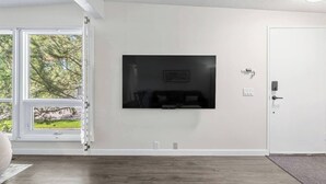 A room with a large window, a door, and a mounted television. - 3 Bed | Min to UofC & Hospital | Garage (Calgary)