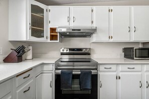 A kitchen with white cabinets, a stainless steel stove, a microwave, and a knife block. - 3 Bed | Min to UofC & Hospital | Garage (Calgary)