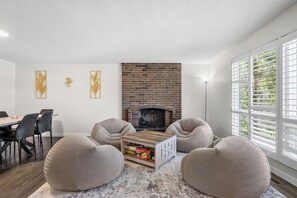 A modern living room with a brick fireplace, comfortable seating, and a dining area. - 3 Bed | Min to UofC & Hospital | Garage (Calgary)