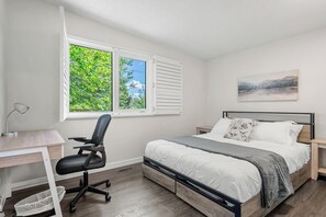Een slaapkamer met een bed, bureau, stoel en een raam met jaloezieën.