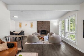 Ein modernes Wohnzimmer mit Kamin, Essbereich und großen Fenstern.