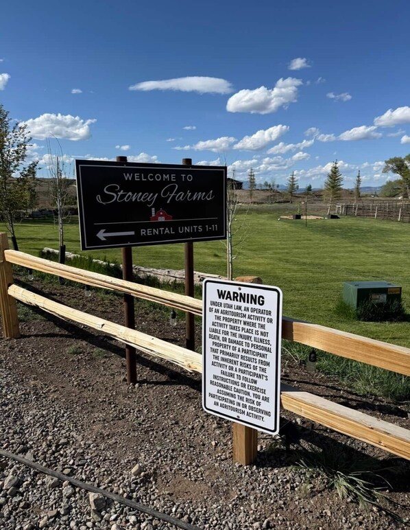 Señal de bienvenida para las unidades de alquiler de Stoney Farms 1-11, una señal de advertencia y una valla de madera.