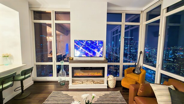 Un salon moderne doté d’un grand téléviseur, d’une cheminée et offrant une vue sur la ville.