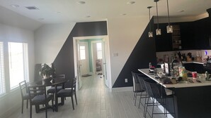 Una cocina moderna con comedor, decoración en blanco y negro, y una escalera que sube a otro nivel.