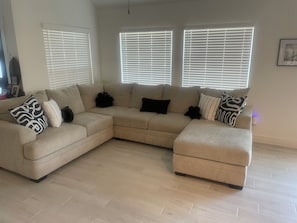 Ein L-förmiges Ecksofa mit mehreren Kissen, einem Flachbildfernseher und einem gerahmten Bild an der Wand.