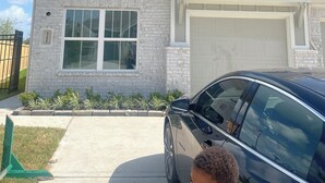 Una casa residencial con garaje, entrada para vehículos y un coche estacionado.