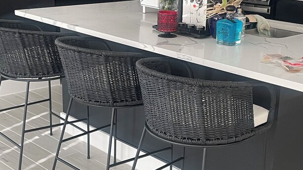 Una cocina moderna con una isla central, taburetes de bar y diversos utensilios de cocina.