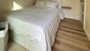 Ein Schlafzimmer mit einem Bett, Holzbalken, einer Klimaanlage, einer Wandleuchte und Holzboden.