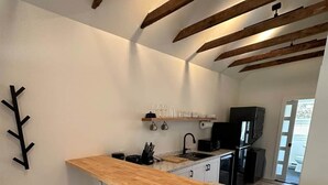 Eine moderne Küche mit einer Holzinsel, Barhocker und freiliegenden Holzbalken.