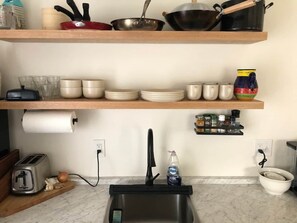 A kitchen with a sink, a toaster, a bowl of onions, and a roll of paper towels. - Charming & Quaint 1 bed in Historic Uptown! (Kingston)