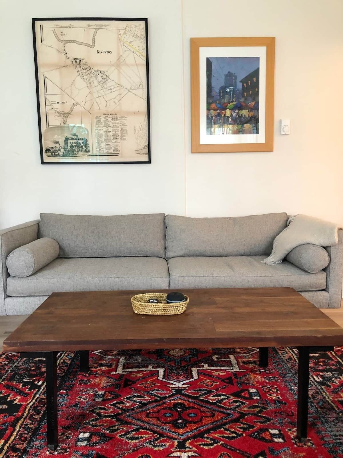 Un salon avec un canapé, une table basse, une carte et un tableau encadré au mur.