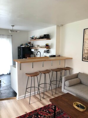 A compact living space with a kitchenette, a sofa, a coffee table, and a patterned rug. - Charming & Quaint 1 bed in Historic Uptown! (Kingston)