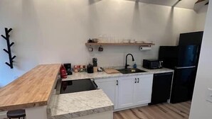 A modern kitchen with a wooden countertop, white cabinetry, and a built-in dishwasher.