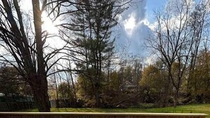 A hot tub on a wooden deck with a view of trees and a fence in the background.