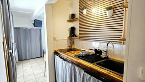 Eine Küche mit Holztischplatte, Spüle, integriertem Backofen und einem Fenster mit Jalousien.