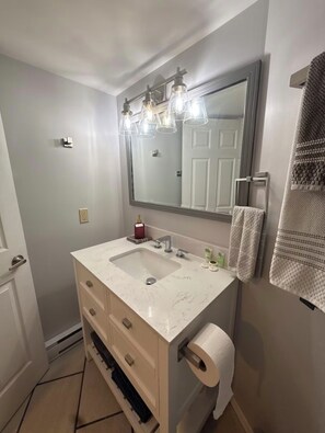 A bathroom with a large mirror, two sinks, a towel rack, and a toilet paper holder. - Trails End Beach House 1 bedroom plus cabin bedroom (Ladysmith)