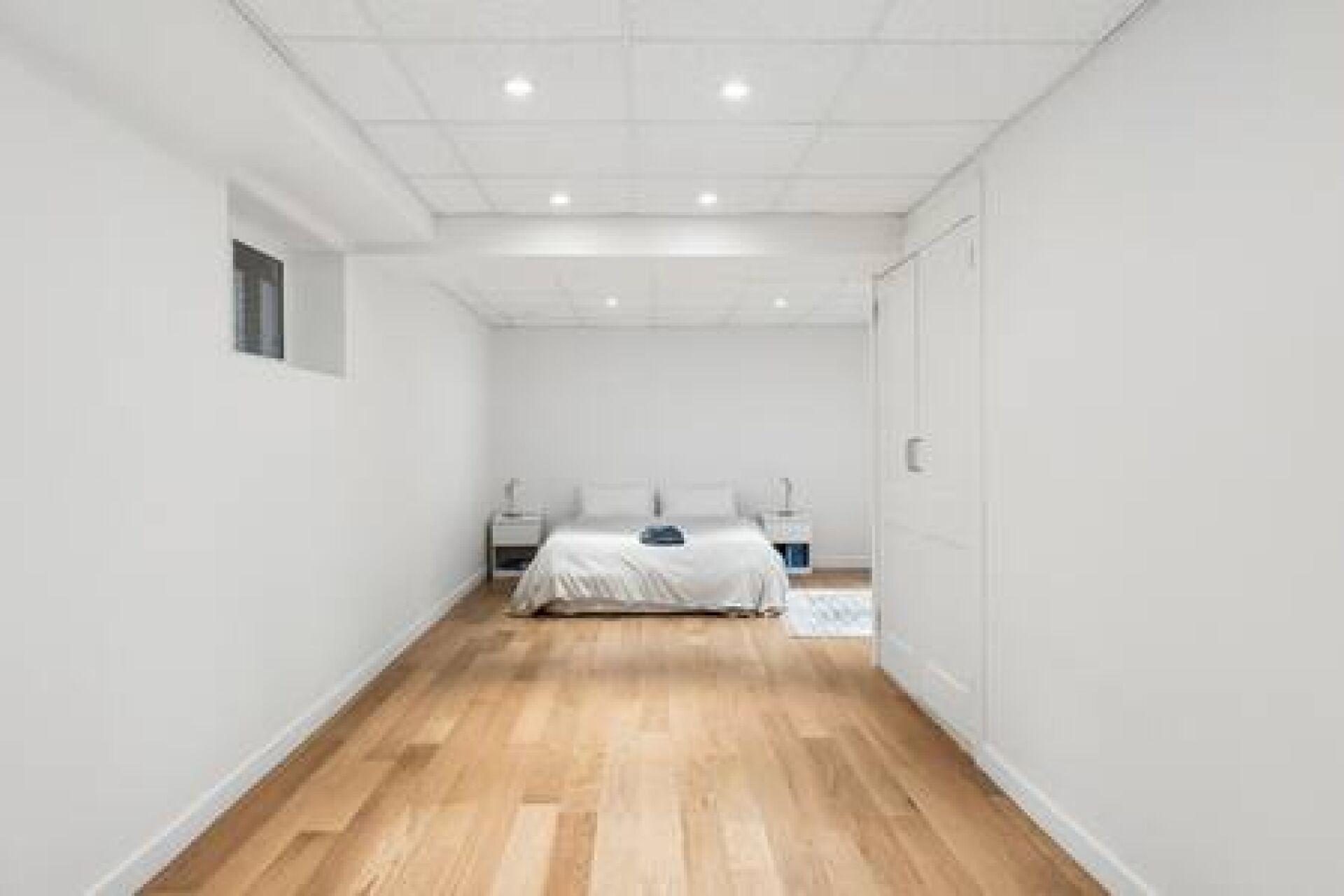 Ein schmaler Flur führt zu einem Schlafzimmer mit Bett, Nachttischen und einem Kleiderschrank.