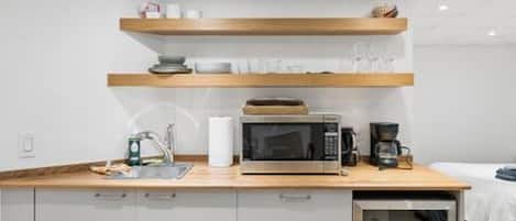 A kitchenette with a microwave, coffee maker, and storage cabinets.