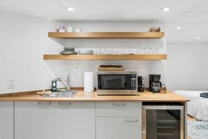 A kitchenette with a microwave, coffee maker, and storage cabinets.