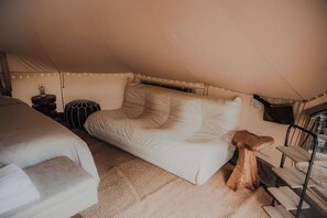 Ein gemütliches Zelt mit einem Bett, einem kleinen Tisch und einem Holzhocker.