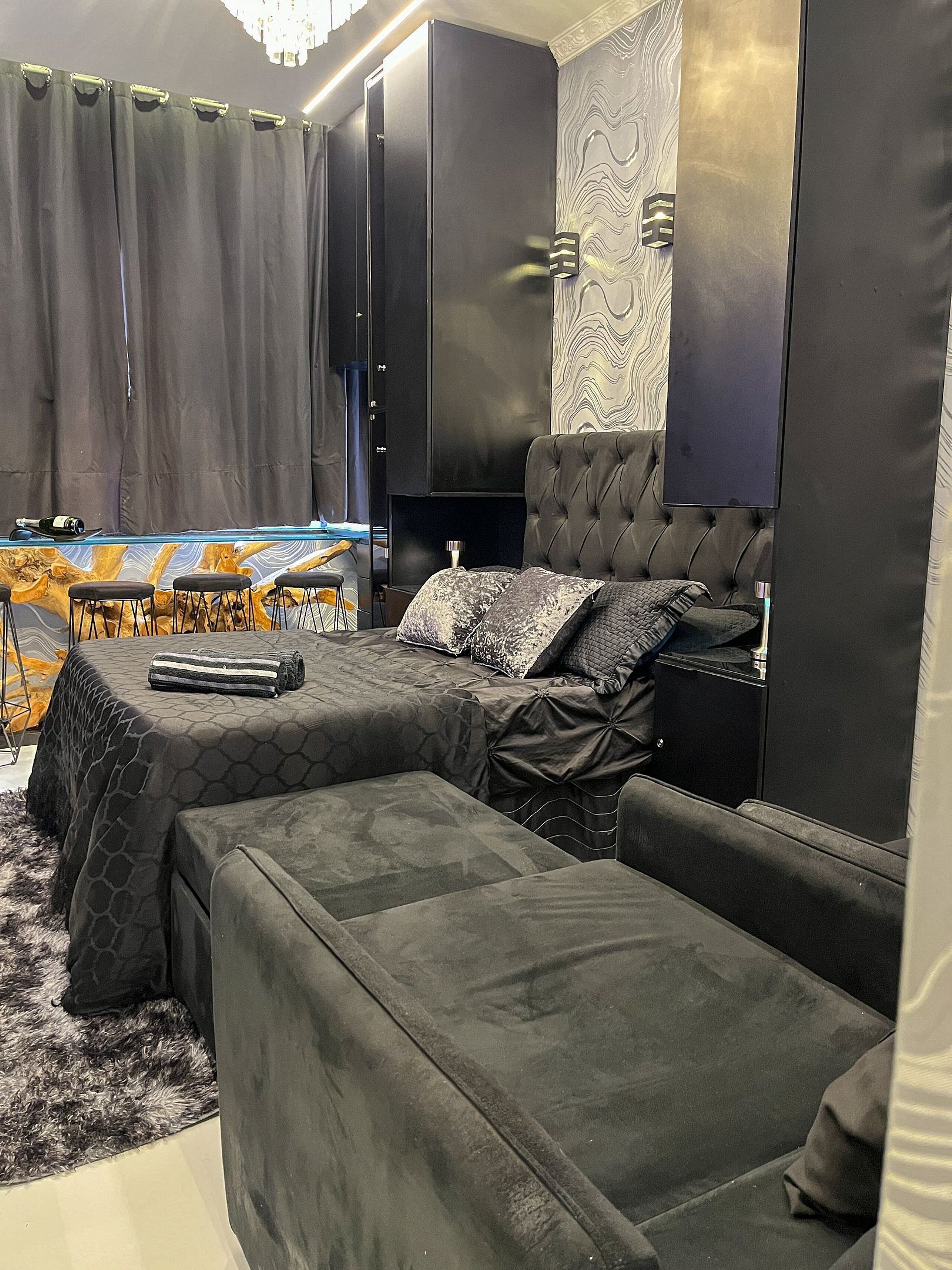 A bedroom with a bed, a sofa, a TV, and a wardrobe.
