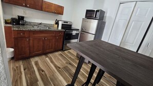 A kitchen with wooden cabinets, a granite countertop, a microwave, a refrigerator, and a dining table. - Cozy & Central 1-Bedroom | Near the Design District (Miami)